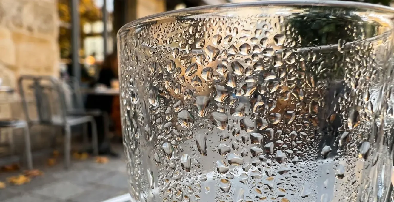 Vue macro de condensation sur verre de café avec terrasse parisienne floue en arrière-plan